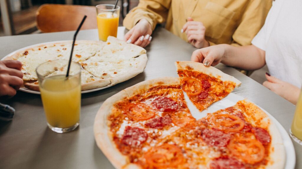 dos personas comienso pizza con jugo de naranja